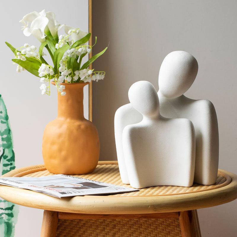 Together For Life decorative figurines handcrafted from fine ceramic, symbolizing love and commitment, placed on a wooden table with a vase of flowers.