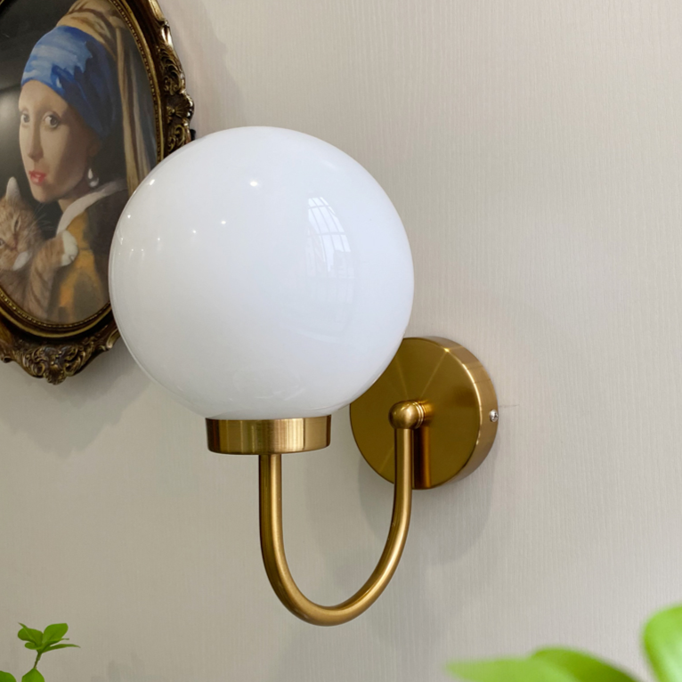 Celestial Orb Wall Lamp showcasing its elegant swoop-style arm and glossed glass lampshade in a modern setting.