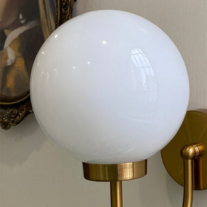 Celestial Orb Wall Lamp showcasing its elegant swoop-style arm and glossed glass lampshade in a modern setting.