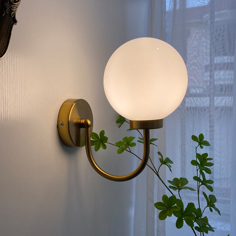 Celestial Orb Wall Lamp showcasing its elegant swoop-style arm and glossed glass lampshade in a modern setting.