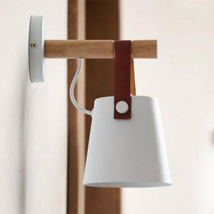 Rustic Elegance Belted Wall Lamp illuminating a cozy reading nook, showcasing its unique blend of metal, wood, and leather.
